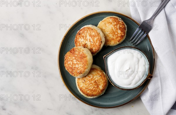 Fried, Cottage cheese pancakes, with sour cream, Cheesecakes, on a marble table, top view, no people