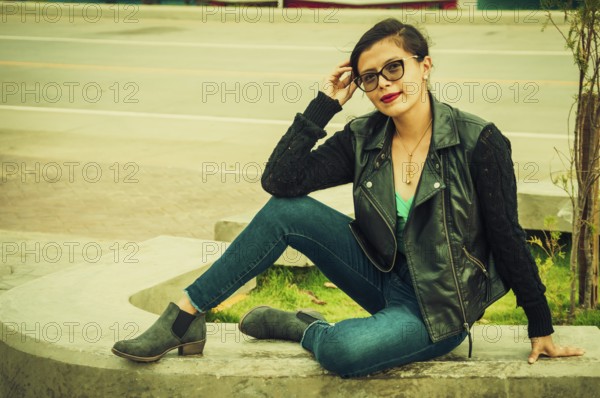 Portrait of beautiful latin girl sitting on a bench. attractive young woman with glasses sitting on a bench