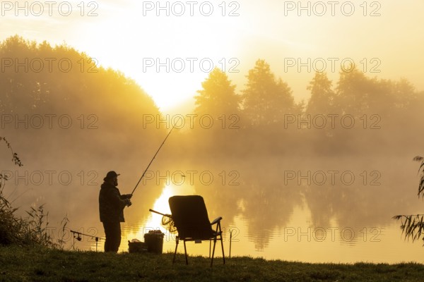 Angler on the bank at sunrise in the fog at the Grutschenteich in Nassau, Weinböhla, Saxony, Germany, Europe