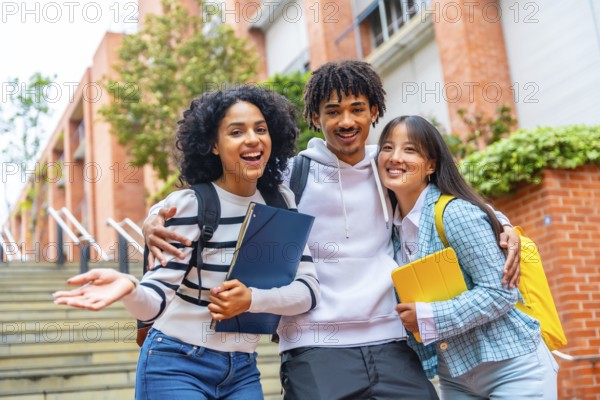 Low angle view portrait of three happy students posing smiling at camera in the campus