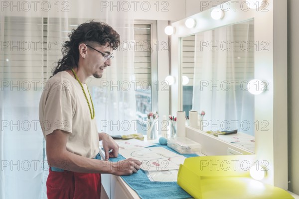 Young male make-up artist carefully reviewing face charts, preparing for diverse clientele in a brightly lit beauty salon, demonstrating inclusivity and attention to detail