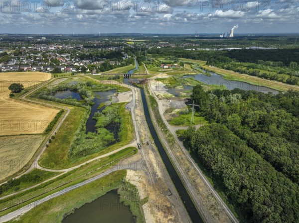 Dortmund / Castrop-Rauxel, North Rhine-Westphalia, Germany, renaturalisation of the Emscher, flood retention basin HRB Mengede. A new floodplain landscape for flood protection and biodiversity is being created at the Emscher-Auen farm. The Emscher, which is currently straightened, will be given curves again and can meander through its new floodplain. The Emscher has been completely free of sewage since 2022 following the construction of a parallel sewer. The river was previously an open, above-ground mixed water channel with rainwater and wastewater. The Uniper coal-fired power plant Datteln 4 in the background, Europe