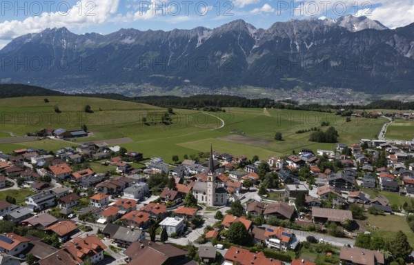 Drone shot, view of village with parish church and Karwendel mountains, Rinn, Tyrol, Austria, Europe