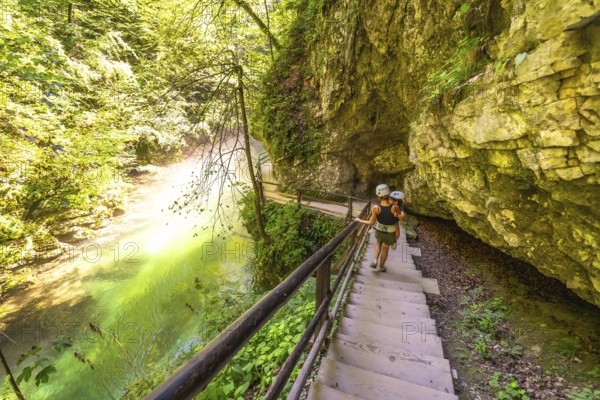 Tourists wearing helmets are walking down wooden stairs along the radovna river in vintgar gorge, a popular tourist destination near bled, slovenia