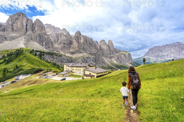 Tourists enjoying a summer hike through the stunning dolomites near gardena pass, italy, surrounded by breathtaking landscapes and vibrant meadows