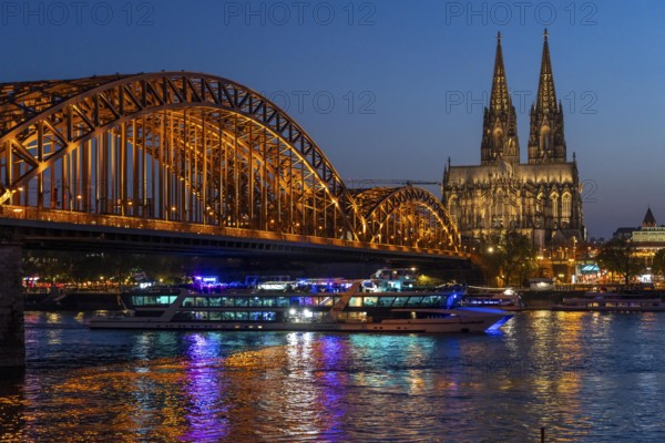 Cologne Cathedral, has been shining in new light since Easter 2025, the old metal halide lamps have been replaced by over 700 modern LED lamps, reducing energy consumption by around four-fifths, significantly improving the quality of light and greatly reducing light emissions, 12 KM of new cables were laid for this, KD Party Schiff, Hohenzollernbrücke, railway bridge over the Rhine, North Rhine-Westphalia, Germany, Europe