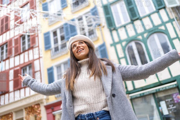 Low angle view photo of a happy stylish woman raising arms in the middle of street while visiting a city