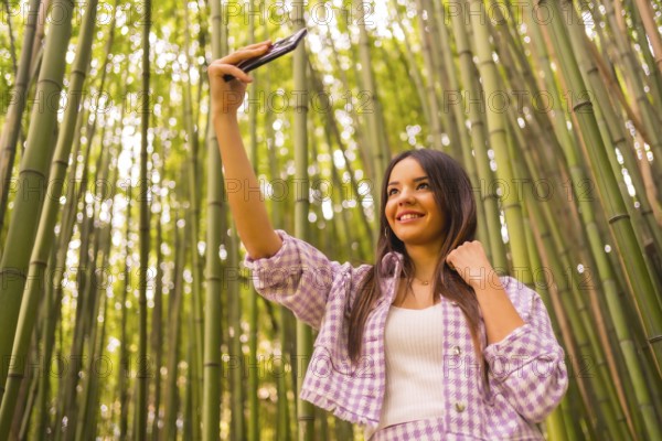 Young caucasian girl with a pink skirt in a bamboo forest. Enjoying summer vacation in a tropical climate, lifestyle of a girl doing a selfie smiling in the forest
