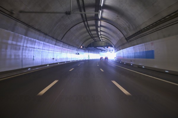 Modern, well-lit motorway tunnel with blue illuminated walls and a clear asphalt road, Switzerland, Europe