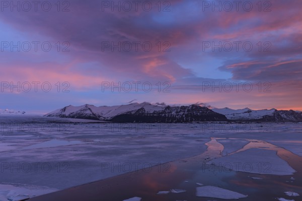 Dawn over frozen lake and mountains, winter, Jökulsarlon, Vatnajökull, Iceland, Europe