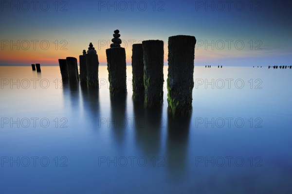 Stone pyramids on old groynes with algae in the water on the beach of the Baltic Sea, long exposure at sunset, Wustrow, Fischland-Darß-Zingst peninsula, Mecklenburg-Vorpommern, Germany, Europe