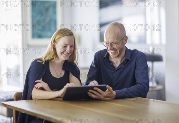 Symbolic photo. A woman and a man sit together at a table with a tablet and talk. Berlin, 13.08.2024