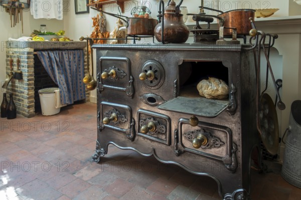 Antique cast-iron stove in kitchen inside 18th century clergy house Schriek at recreated village in open air museum Bokrijk, Limburg, Belgium, Europe