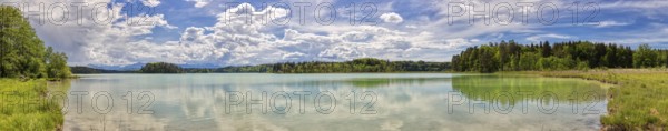 Lake with clear water surface, cloudy sky and surrounding green nature, Easter Lakes