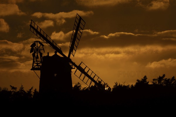 Windmill silhouette at sunset with a red sky and clouds behind, Cley-next-to-the-sea, Norfolk, England, United Kingdom, Europe