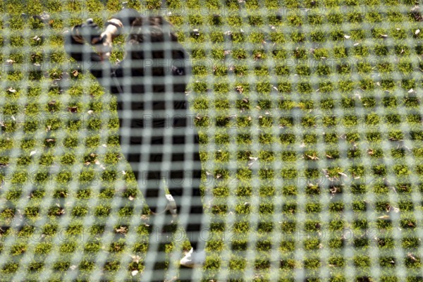 Golfer Training on Driving Range Behind a Net