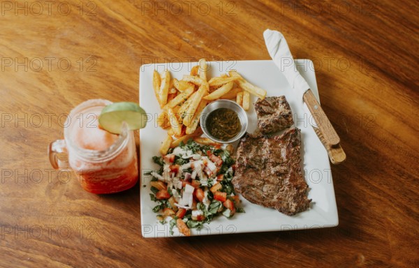 Plate of skirt steak with french fries and drink served on wooden table. Delicious homemade steak with healthy juice