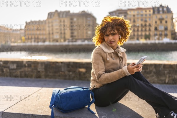 Side view with copy space of a latin beauty woman using phone sitting next to the river at city