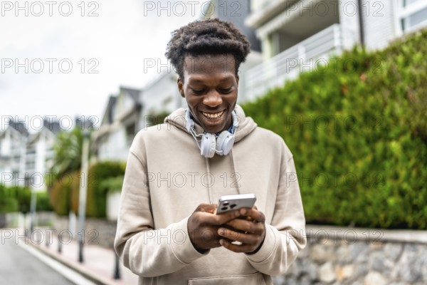 Confident african young man smiling while using phone standing in a residential street