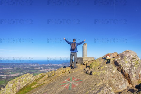 A male hiker celebrating the climb to the top of Mount Adarra in Urnieta. Gipuzkoa, Basque Country