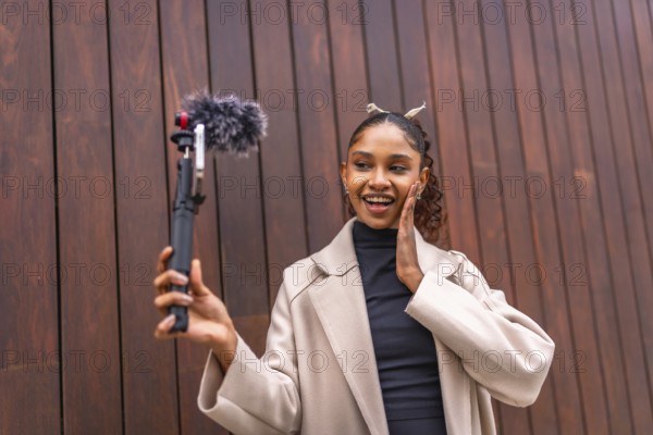 Cute and beauty african american woman recording vlog in the city next to a wooden wall