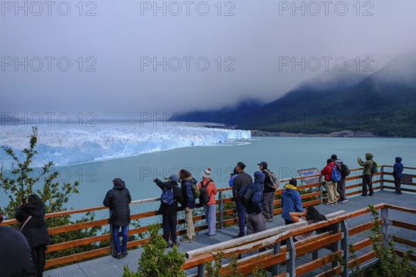 El Calafate, Patagonia, Argentina, Perito Moreno Glacier in Los Glaciares National Park. The Perito Moreno Glacier is part of the Patagonian ice field, the Campo Hielo Sur, the third largest freshwater reserve in the world. It is located in the province of Santa Cruz on Lago Argentino, the country's largest lake. The Perito Moreno Glacier is up to 30 kilometres long and 5 kilometres wide. Its edge is 70 metres high at its highest point. Small icebergs that have broken off from the glacier float in Lago Argentino. The glacier is one of the most beautiful sights in South America and is one of the most visited attractions in Argentina. Tourists stand on a viewing platform, South America