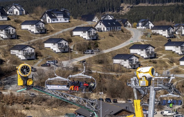 Winter sports area in the Sauerland, Winterberg ski lift carousel, artificial snow slopes, artificial snow from over 360 snow guns, Poppenberg ski area, 12 of 24 lifts are in operation in mid-March, the rest of the landscape is snow-free, in the background holiday homes at Landal Ferienpark Winterberg, North Rhine-Westphalia, Germany, Europe