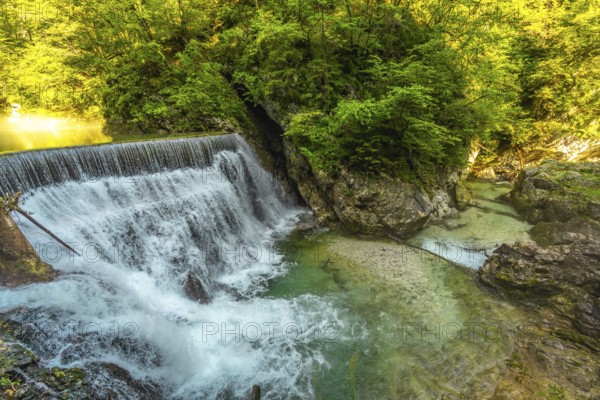 Stunning waterfall cascading into the crystal clear turquoise waters of vintgar gorge, a natural wonder near bled, slovenia, surrounded by lush green forest