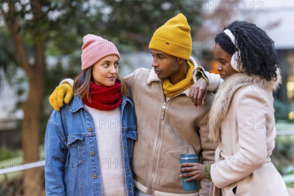Group of cheerful multi ethnic friends wearing winter clothes, walking together on a cold winter day, having fun and talking