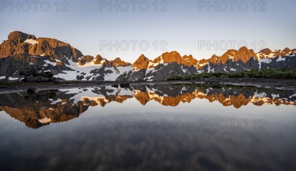 Rocky mountain peaks reflected in a small pond, mountain landscape with alpenglow at sunrise, at the Trollfjord Hytta, at the Trollfjord, Lofoten and Vesterålen, Nordland, Norway, Europe
