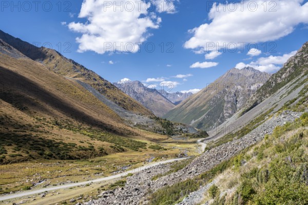 Gravel track in a valley, picturesque mountain landscape with white mountain peaks, Tian Shan Mountains, Issyk-Kul, Kyrgyzstan, Asia