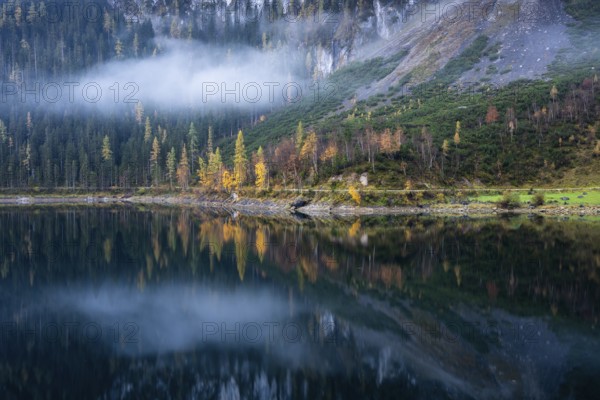 The Vordere Gosausee in autumn. Part of the path around the lake, with a cloud. Trees in autumn leaves. Reflection. Vorderer Gosausee, Gosau, Gosau Valley, Salzkammergut, Upper Austria, Austria, Europe