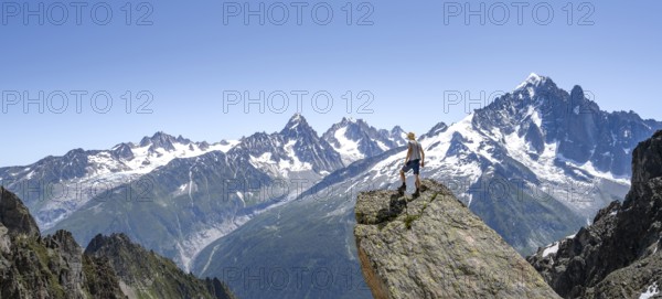 Mountaineer standing on a rock, mountain landscape with mountain peak Aiguille Verte, Mont Blanc massif, Aiguilles Rouges, Chamonix-Mont-Blanc, Haute-Savoie, France, Europe