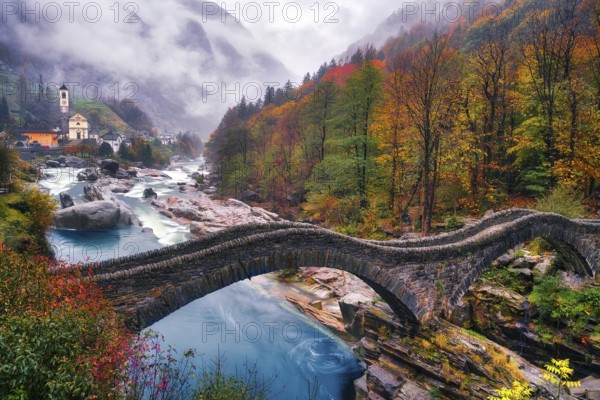 Stone bridge Ponte dei Salti over river Verzasca on a rainy autumn day, behind it village view Lavertezzo, Verzasca Valley, Canton Ticino, Switzerland, Europe