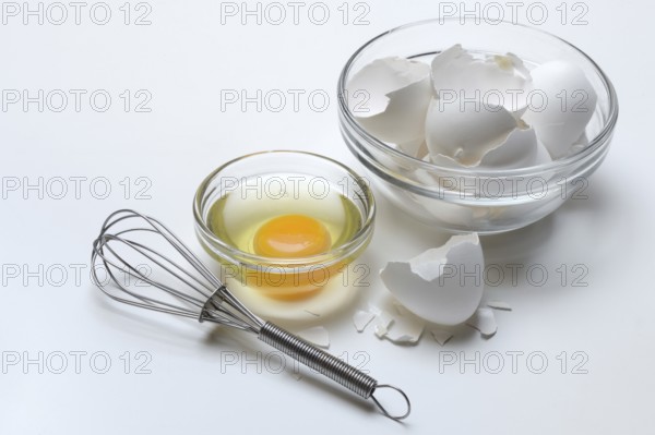Egg whites and egg yolks in glass bowl and egg shells, whisk