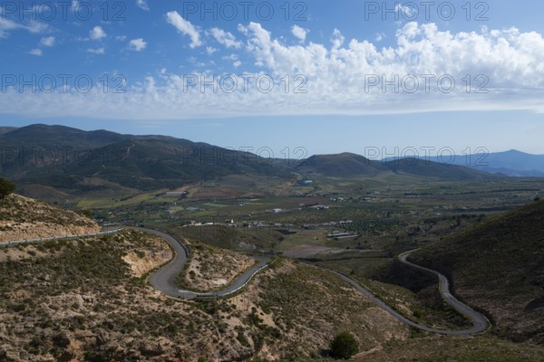 Mountain landscape with serpentine road in green valley under blue sky with clouds, road to Mirador Laujar, Laujar de Andarax, Almería province, Almeria, Andalusia, Spain, Europe