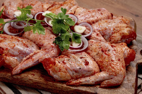 Chicken wings, marinated and laid out on a wooden platter, ready for cooking, grilling or baking, in a home kitchen, there are no people