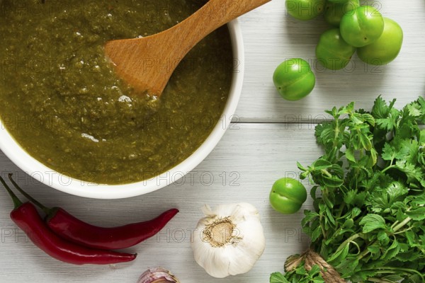 Tkemali sauce, traditional Georgian cuisine, green cherry plum, with ingredients for sauce, cilantro, mint, hot pepper, garlic, on a white wooden table, close-up, rustic, food background, no people, selective focus, sauce, green sauce, tkemali, georgian cuisine, homemade