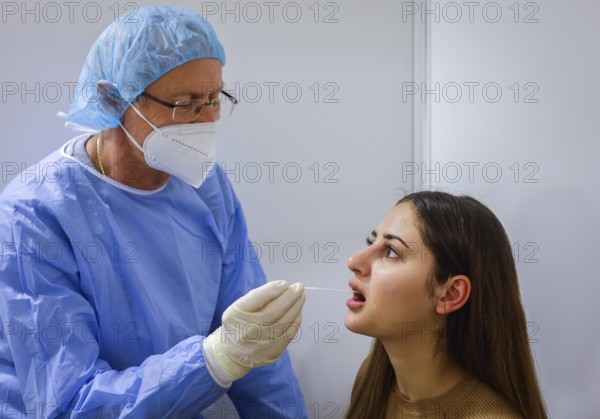 Essen, North Rhine-Westphalia, Germany - Corona test centre Grugahalle open for free citizen test, Covid rapid test, a doctor tests a young woman for the coronavirus using a throat swab, from 8 March, German citizens can be tested for corona once a week free of charge at the rapid test centre