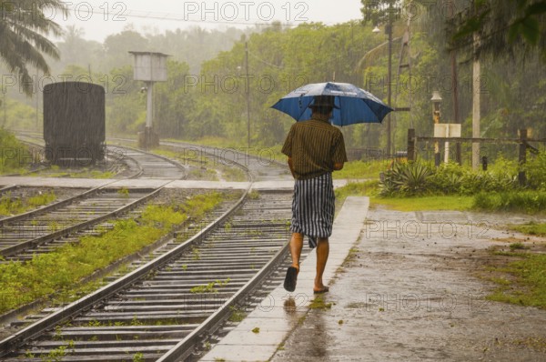 Sinhalese with umbrella in heavy rain, monsoon, railway station in Kalawewa, Sri Lanka, Ceylon, South Asia Asia, Asia