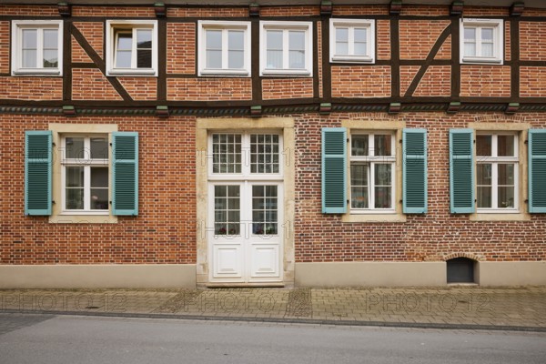 Facade of a half-timbered brick house with white windows, a mighty entrance door and blue-green shutters in Warendorf, Warendorf district, North Rhine-Westphalia, Germany, Europe