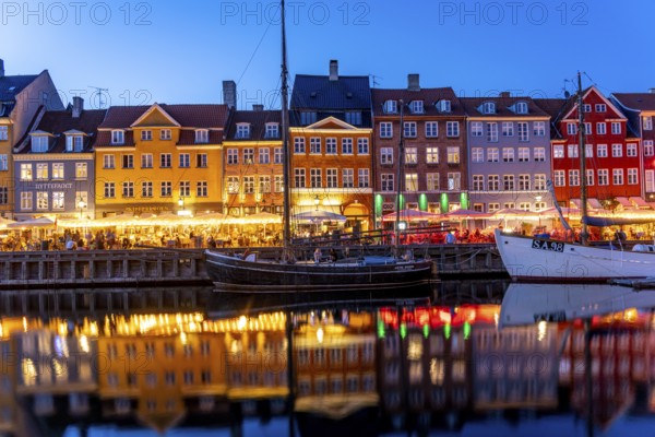 Colourful houses, restaurants and historic ships on the Nyhavn canal and harbour at dusk, Copenhagen, Denmark, Europe