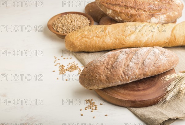 Different kinds of fresh baked bread on a white wooden background. side view, close up, copy space