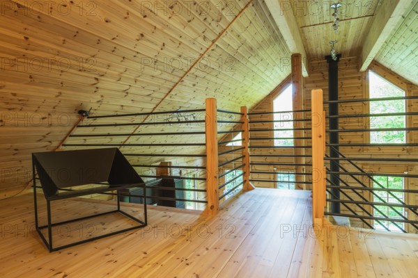 Black metal sitting chair and tubular railings with wooden posts in home office set-up on mezzanine inside a piece sur piece Scots pine log home, Quebec, Canada, North America