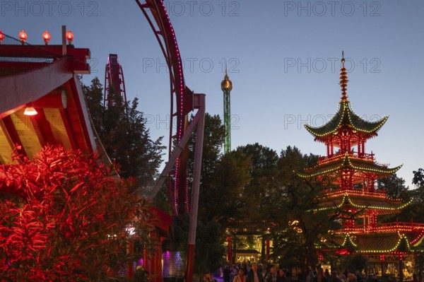 Red and yellow illuminated pagoda, roller coaster, Tivoli Amusement and Recreation Park, Copenhagen, Denmark, Europe
