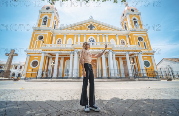 Beautiful tourist taking a selfie on the street of the cathedral in Granada, Nicaragua Young woman traveler taking a selfie in a public square in front of a cathedral