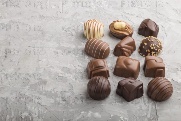 Different chocolate candies on a gray concrete background. side view, copy space