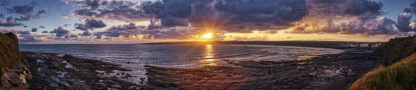 Impressive sunset over the sea, bright orange-red sky, rocks in the foreground, Lahinch Beach