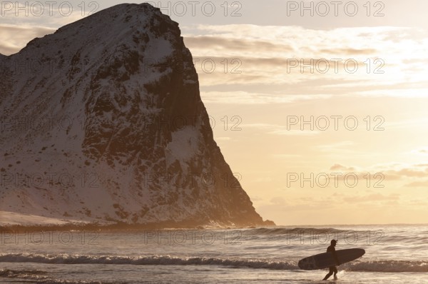 Surfer with surfboard under his arm on the beach of Unnstad, winter surfing, Lofoten Island Vestvågøya Lofoten, Northern Norway, Norway, Europe