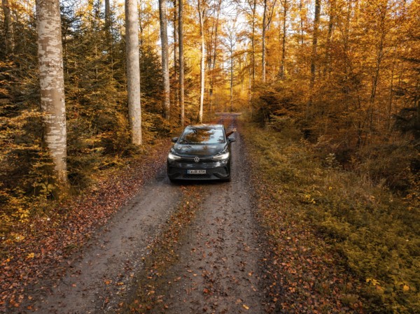 Car standing on a forest path, surrounded by autumn trees and leaves, electric car, VW ID5, Gechingen, Black Forest, Germany, Europe